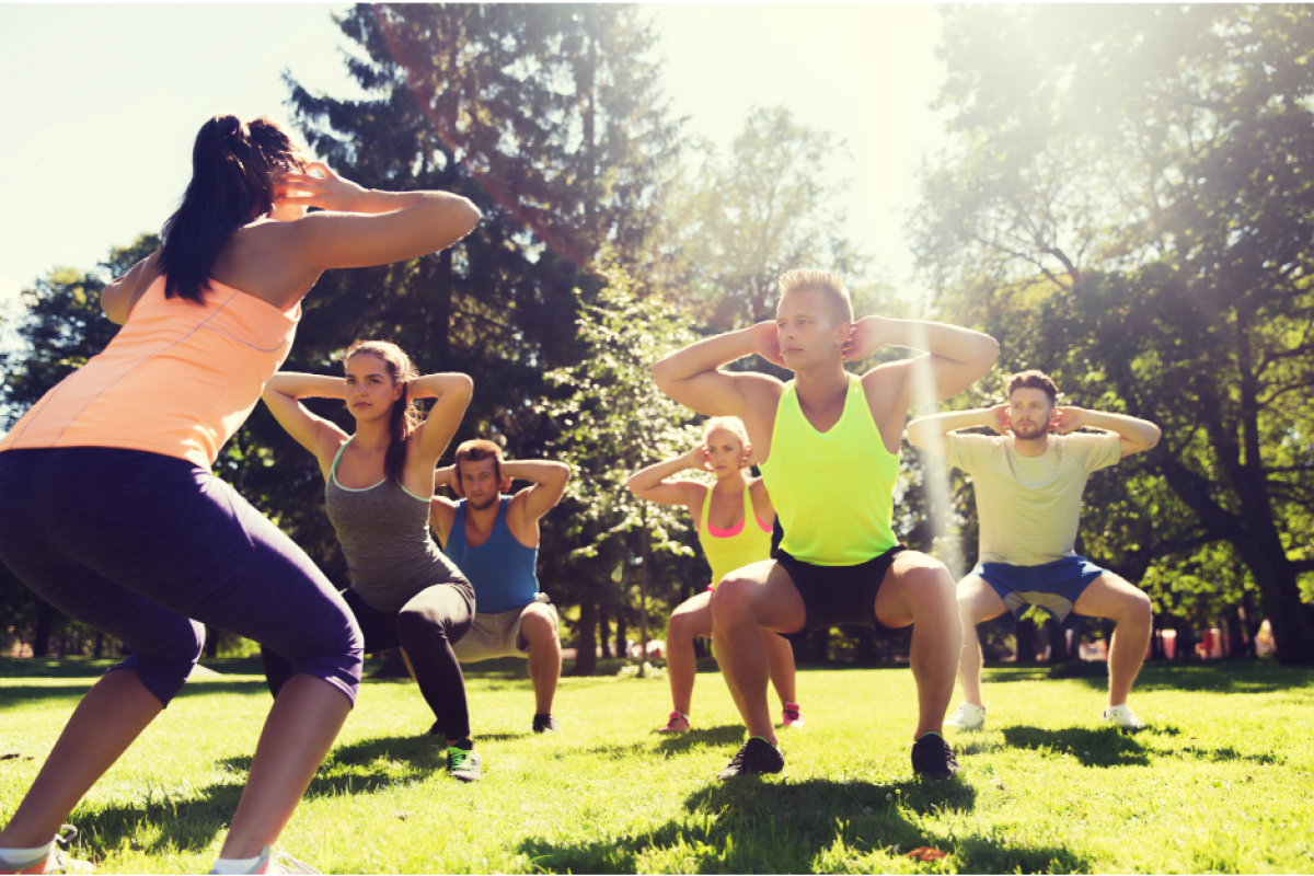 diverse group of people participating in a bootcamp workout outdoors, with a focus on camaraderie and determination.